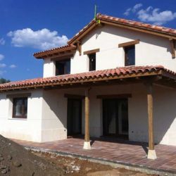 Imagen de obra nueva de chalet de dos plantas, fachada blanca y porche con vigas de madera